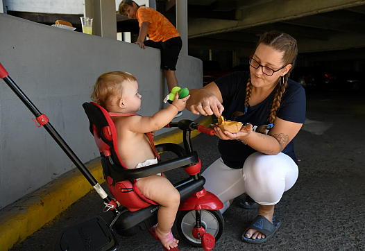 Person kneeling by a child in a stroller